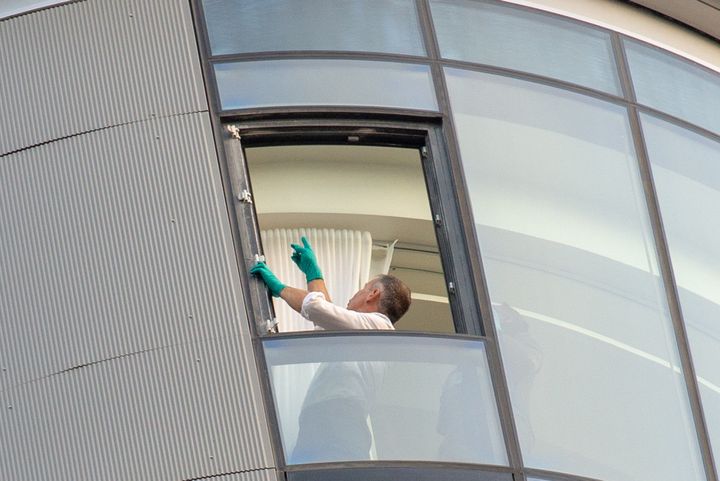 An investigator assesses the open window on the 27th floor of The Corniche development.
