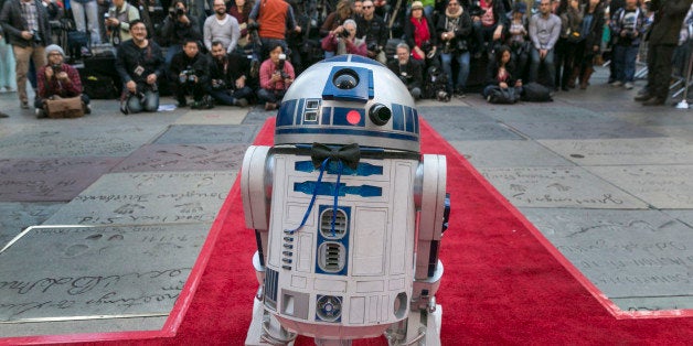 Members of the media are seen as Star Wars' movie character R2-D2 wearing a black bow tie glides down the red carpet for the wedding of Star Wars fans, Caroline Ritter and Andrew Porters, from Australia who are getting married at the forecourt of Hollywood's TCL Chinese Theatre IMAX in Los Angeles Thursday, Dec. 17, 2015. The new movie sequel âStar Wars: The Force Awakensâ begins screening tonight. (AP Photo/Damian Dovarganes)