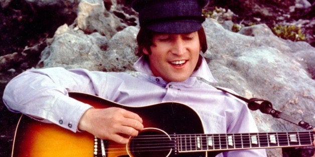 CIRCA 1964: Guitarist John Lennon of the rock and roll band 'The Beatles' poses for a portrait while strumming a Gibson acous