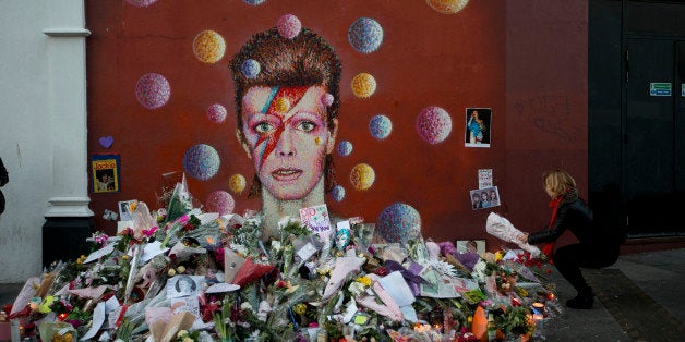 A woman lays flowers beside a mural of British singer David Bowie by artist Jimmy C in Brixton, south London, Tuesday, Jan. 1