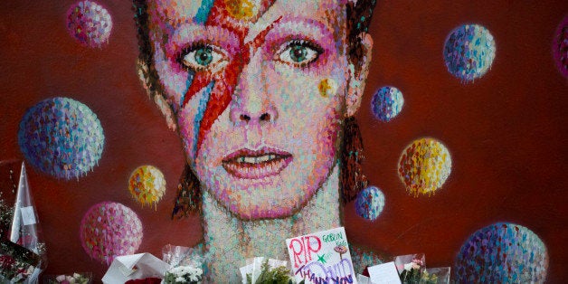 Tributes lie beneath a mural of British singer David Bowie by artist Jimmy C in Brixton, south London, Tuesday, Jan. 12, 2016. Bowie, the other-worldly musician who broke pop and rock boundaries with his creative musicianship, nonconformity, striking visuals and a genre-spanning persona he christened Ziggy Stardust, died of cancer Sunday aged 69. He was born in Brixton. (AP Photo/Matt Dunham)