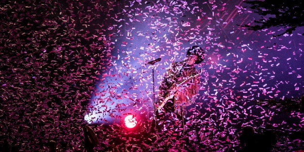 Singer and musician Prince plays a guitar solo while confetti (of course coloured purple) is flying around over the concert c