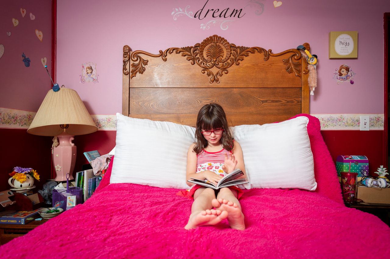 Tessa, 7, of Lafayette, Indiana, reads a book in her bright pink bedroom.