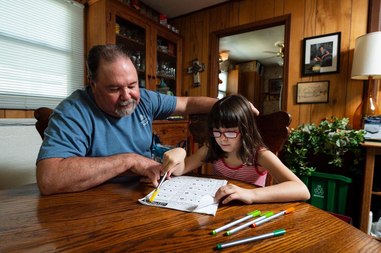 Kevin O'Brien, left, works with Tessa, 7, on her school work.