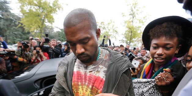 US musician Kanye West signs autographs after Celine 2014 Spring/Summer ready-to-wear collection fashion show, on September 29, 2013 in Paris. AFP PHOTO / JOEL SAGET (Photo credit should read JOEL SAGET/AFP/Getty Images)