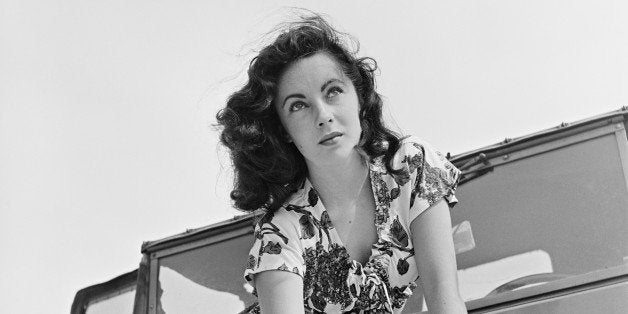 Portrait of actress Elizabeth Taylor painting while sitting on the hood of a jeep vehicle, California, June 1947. (Photo by KM Archive/Getty Images)