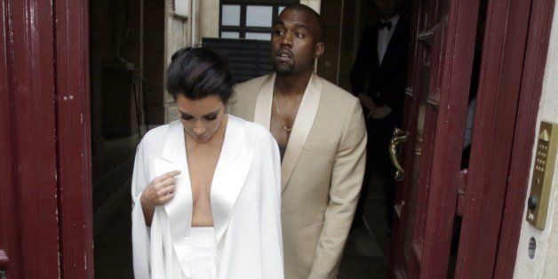 American reality TV star Kim Kardashian (L) and American singer Kanye West (R) leave their residence in Paris on May 23, 2014, ahead of their wedding. Kanye West and his bride-to-be Kim Kardashian lunched on May 23 at a French chateau owned by iconic designer Valentino, kicking off a marathon celebration expected to culminate in the wedding of the year. AFP PHOTO / KENZO TRIBOUILLARD (Photo credit should read KENZO TRIBOUILLARD/AFP/Getty Images)