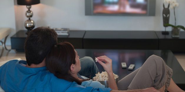Couple watching television together and eating popcorn