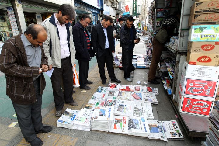 Iranian men look at newspapers displayed at a kiosk in central Tehran on March 1, 2012 on the eve of a parliamentary election. Iran's 48 million voters are being called on to decide their next parliament on March 2 in elections whose turnout will be weighed to give an idea of support for the Islamic republic's regime. AFP PHOTO/ATTA KENARE (Photo credit should read ATTA KENARE/AFP/Getty Images)