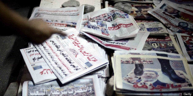 An Egyptian man points at a pile of newspapers reporting on the toppling of ousted Egyptian president Mohamed Morsi on July 4, 2013 in Cairo. Egypt's chief justice Adly Mansour was sworn in as the country's interim president, a day after the military ousted and detained Egypt's former Islamist president following days of massive protests. AFP PHOTO/MOHAMED EL-SHAHED (Photo credit should read MOHAMED EL-SHAHED/AFP/Getty Images)