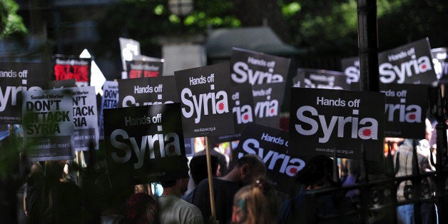 Protesters holds signs during a protest against military intervention in Syria in central London on August 31, 2013. British lawmakers voted late on August 29 to reject Prime Minister David Cameron's call for British involvement in military strikes aimed at punishing the Syrian regime for alleged chemical weapons use. AFP PHOTO/CARL COURT (Photo credit should read CARL COURT/AFP/Getty Images)