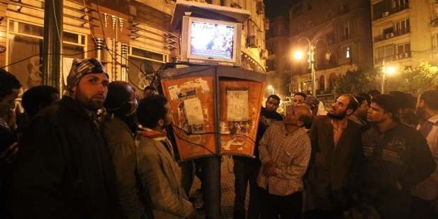 Egyptians gather to watch the Al-Jazeera satellite television station on a set placed on top of public telephone booths in Cairo's Tahrir Square, following a seventh day of protests calling for the removal of President Hosni Mubarak's regime on January 31, 2011. AFP PHOTO/KHALED DESOUKI (Photo credit should read KHALED DESOUKI/AFP/Getty Images)