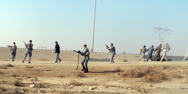 Iraqis security fire into the air as Iraqi deputy premier Saleh al-Mutlak is attacked as he arrived to give a speech on December 30, 2012, forcing him to flee the rally he was addressing on the outskirts of the western city of Ramadi, an AFP reporter said. The demonstrators, who have blocked a key highway connecting Iraq to Syria and Jordan for the past week over the alleged targeting of their Sunni Arab minority by the Shiite-led government in Baghdad, threw water bottles, stones and shoes at Mutlak before grabbing and hitting him. AFP PHOTO/AZHAR SHALLAL (Photo credit should read AZHAR SHALLAL/AFP/Getty Images)