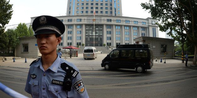 Police stand guard as officials arrive for the trial of disgraced politician Bo Xilai on the fourth day of Bo's trial at the Intermediate People's Court in Jinan, Shandong Province on August 25, 2013. Once one of China's highest-flying politicians, Bo Xilai found himself in the criminal dock on trial for bribery and abuse of power in the country's highest-profile prosecution in decades. His downfall began when a British businessman was found dead in a hilltop hotel room. As the drama finally nears its conclusion, the Communist Party is touting it as proof of its intent to crack down on corruption. AFP PHOTO/Mark RALSTON (Photo credit should read MARK RALSTON/AFP/Getty Images)