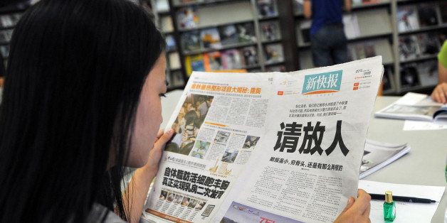 A woman reads the New Express newspaper that on October 23, 2013 carried a full-page editorial with headline 'Please release our man', in a library in Guangzhou, south China's Guangdong province. The New Express tabloid, based in Guangzhou, published a front-page call on October 23 for police to free a journalist detained after reporting 'financial problems' at a partly state-owned company, in a rare example of media defying authorities. CHINA OUT AFP PHOTO (Photo credit should read STR/AFP/Getty Images)