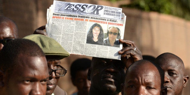 A Malian journalist holds a local newspaper showing on frontpage the portraits of Radio France Internationale (RFI) journalis