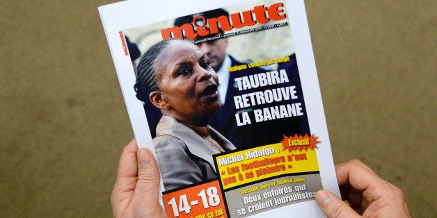 A picture taken on November 12, 2013 in Paris shows a person holding a reproduction of the front page of French far-right weekly magazine 'Minute' with a picture of French Justice Minister Christiane Taubira entitled 'Maligne comme un singe, Christiane Taubira retrouve la banane' ('Clever as a monkey, Taubira gets her bounce back'). The magazine headlined on its November 13, 2013 issue this sentence as a relay to repeated racial slurs that have recently targeted the Minister of Justice. 'Recovering banana' is a familiar formula which mean, 'recovers her form'. Taubira was recently compared to a monkey by a then French far-right party Front national member, then by a child saying : 'A banana to the monkey'during an hostile demonstration to the minister by anti-'marriage for all' militants.' AFP PHOTO PIERRE ANDRIEU (Photo credit should read PIERRE ANDRIEU/AFP/Getty Images)