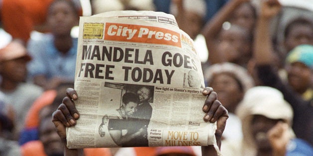 A jubilant Sowetan holds up 11 February 1990 in Soweto a newspaper announcing the release of anti-apartheid leader and African National Congress (ANC) member Nelson Mandela, at a mass ANC rally. South African President de Klerk lifted 02 February the 30-year-old ban on the ANC and the South African Communikst Party, and 11 February, Nelson Mandela walked out of Victor Vester prison, near Cape Town, after 26 year since he was sentenced to life imprisonment. (Photo credit should read TREVOR SAMSON/AFP/Getty Images)