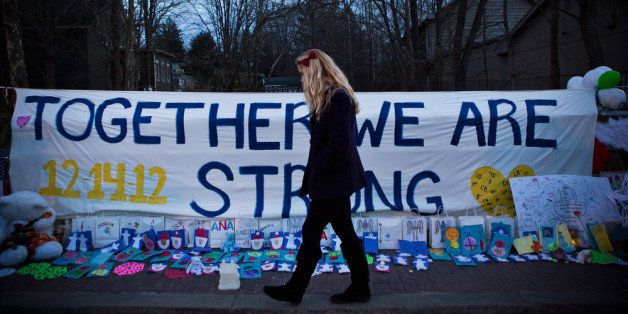 NEWTOWN, CT - DECEMBER 24: A woman walks past a sign that reads 'Together we are Strong' at a memorial for those killed in the school shooting at Sandy Hook Elementary School on December 24, 2012 in Newtown, Connecticut. Donations and letters are pouring in from across the country as the town tries to recover from the massacre. (Photo by Andrew Burton/Getty Images)