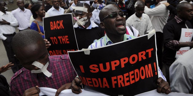 Kenyan journalists, some covering their mouths with tape, hold signs during a protest against a controversial bill that they say would allow the government greater control over the press in Nairobi on December 3, 2013. If passed, the bill would give the government greater freedom to seize journalists' equipment, search their postal mail and impose hefty fines to media houses and journalists. AFP PHOTO/SIMON MAINA (Photo credit should read SIMON MAINA/AFP/Getty Images)