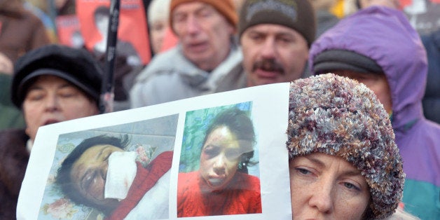 Protesters hold photos of Tetyana Chornovol, popular Ukrainian journalist and opposition activist, during the rally at the Internal Affairs Ministry in Kiev on December 26, 2013. Tetyana was beaten by unknown people after they attacked her car on the Wednesday night. Protesters demand the minister Vitaliy Zakharchenko's resignation as they link the attack to Chornovil with her professional activities directed by harsh criticism of authorities and accused the police and other security services in the organization of this and other attacks on opposition activists last week.AFP PHOTO / SERGEI SUPINSKY (Photo credit should read SERGEI SUPINSKY/AFP/Getty Images)