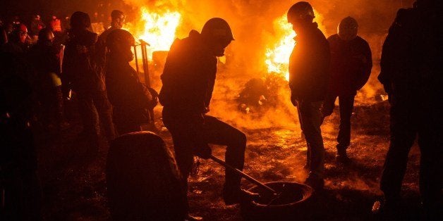 Activists of Euromaidan (the name given for Independence Square) burn tyres and warm themselves at a barricade in the center of Kiev early on January 24, 2014. Crunch talks between the opposition and President Viktor Yanukovych failed Thursday to end Ukraine's crisis but an uneasy truce held after five days of deadly clashes between protesters and security forces. Ukraine's three main opposition leaders held several hours of talks with Yanukovych but the relatively minor concessions offered by the president were greeted with derision by tens of thousands of protesters on Independence Square in Kiev. AFP PHOTO/ VOLODYMYR SHUVAYEV (Photo credit should read VOLODYMYR SHUVAYEV/AFP/Getty Images)