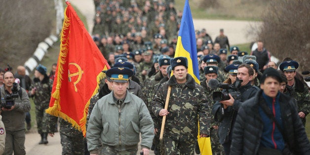 LUBIMOVKA, UKRAINE - MARCH 04: Colonel Yuli Mamchor (L), commander of the Ukrainian military garrison at the Belbek airbase, leads his unarmed troops to retake the Belbek airfield from soldiers under Russian command in Crimea on March 4, 2014 in Lubimovka, Ukraine. After spending a tense night anticipating a Russian attack following the expiration of a Russian deadline to surrender, in which family members of troops spent the night at the garrison gate in support of the soldiers, Mamchor announced his bold plan to his soldiers early this morning. The Russian-lead troops fired their weapons into the air but then granted Mamchor the beginning of negotiations with their commander. Russian-lead troops have blockaded a number of Ukrainian military bases across Crimea. (Photo by Sean Gallup/Getty Images)