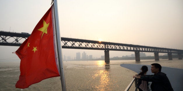 A couple stand near a Chinese national flag on a ferry crossing the Chang Jiang river in Wuhan, China, on Sunday, Oct. 20, 2013. China's economic expansion accelerated to 7.8 percent in the third quarter from a year earlier, the statistics bureau said Oct. 18, reversing a slowdown that put the government at risk of missing its 7.5 percent growth target for 2013. Photographer: Tomohiro Ohsumi/Bloomberg via Getty Images