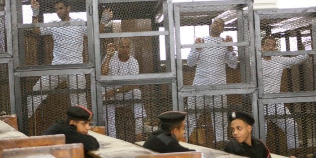 Defendants in the Marriott terror cell case in Cairo stand in cages in an Egyptian courtroom Monday, March 31, 2014, as they await their turn to speak about their request for bail. From left, Suhaib Saeed, a university student who donned a white t-shirt to cover one that compared his prison conditions to Guantanamo, Al Jazeera English correspondent Peter Greste, an Australian, Al Jazeera English bureau chief Mohamed Fahmy, who holds dural Canadian-Egyptian citizenship, and cameraman Baher Mohamed, an Egyptian. The three journalists are accused of falsifying news about Egypt and running a terror cell out of their temporary offices at the Marriott Hotel in Cairo. The judge again denied bail for the men, who've been held since Dec. 29. (Amina Ismail/MCT via Getty Images)