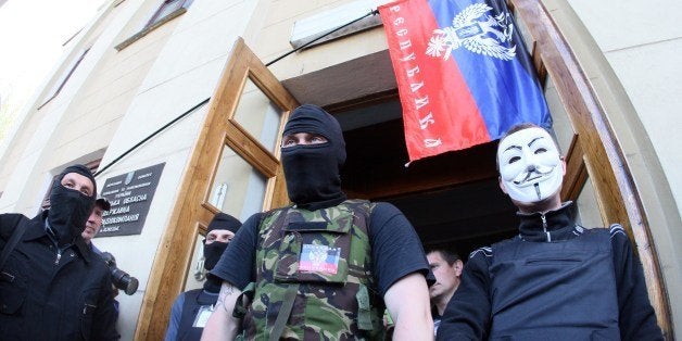 Pro-Russian activists stand guard outside a regional television station after it was seized by pro-Russian separatists, in th
