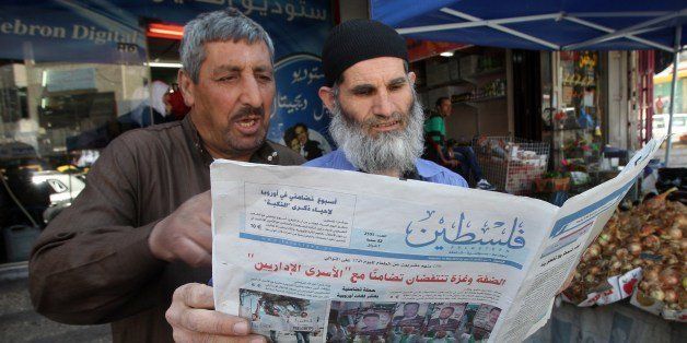 Palestinian men read the Hamas-affiliated newspaper Felesteen (Palestine) in a street of the West Bank town of Hebron on May 10, 2014. The Palestinian Authority lifted ban on Hamas daily which has been distributed for the first time in seven years in the West bank and East Jerusalem. AFP PHOTO / HAZEM BADER (Photo credit should read HAZEM BADER/AFP/Getty Images)