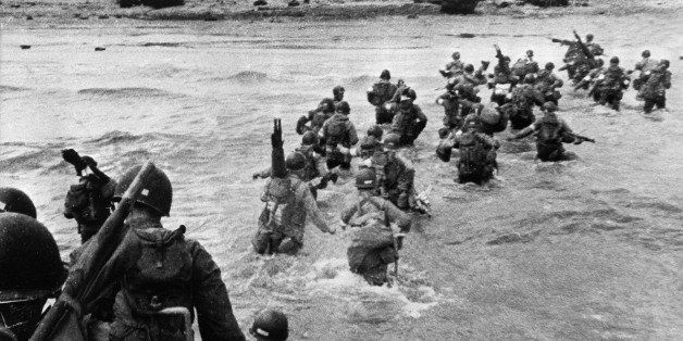 American troops landed on Normandy beaches (north-west of France), to come as reinforcements during the historic D-Day, 06 June 1944, during WW2. American troops supporting those already on the coast of Northern France, plunge into the surf and wade shoreward carrying equipment, on Utah Beach, Les Dunes de Madeleine, France. Bulldozers and other engineer equipment prepare the beach for the landing parties. AFP PHOTO STAFF (Photo credit should read STF/AFP/Getty Images)