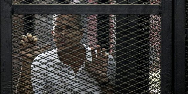 Al-Jazeera news channel's Australian journalist Peter Greste (C) listens to the verdict inside the defendants cage during his trial for allegedly supporting the Muslim Brotherhood on June 23, 2014 at the police institute near Cairo's Tora prison. The Egyptian court sentenced the three Al-Jazeera journalists to jail terms ranging from seven to 10 years after accusing them of aiding the blacklisted Brotherhood. Since the army ousted Islamist president Mohamed Morsi in July 2013, the authorities have been incensed by the Qatari network's coverage of their deadly crackdown on his supporters. AFP PHOTO / KHALED DESOUKI (Photo credit should read KHALED DESOUKI/AFP/Getty Images)