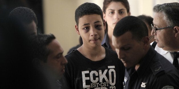 Tariq Abu Khder (C), a Palestinian-US teenager who was allegedly beaten during police custody, arrives for a hearing at Jerusalem Magistrates Court on July 6, 2014. Tariq Abu Khder, who was arrested in Shuafat during violent clashes between stonethrowers and Israeli riot police, 'was given nine days house arrest in Beit Hanina for the duration of the investigation' into stonethrowing allegations, police spokeswoman Luba Samri said in a statement. AFP PHOTO / AHMAD GHARABLI (Photo credit should read AHMAD GHARABLI/AFP/Getty Images)