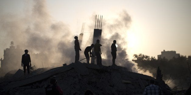 Palestinian men inspect the site of an Israeli military strike in Gaza City on July 08, 2014 . The Israeli air force launched dozens of raids on the Gaza Strip overnight after massive rocket fire from the enclave pounded southern Israel, leaving 17 people injured, sources said. AFP PHOTO / MAHMUD HAMS (Photo credit should read MAHMUD HAMS/AFP/Getty Images)