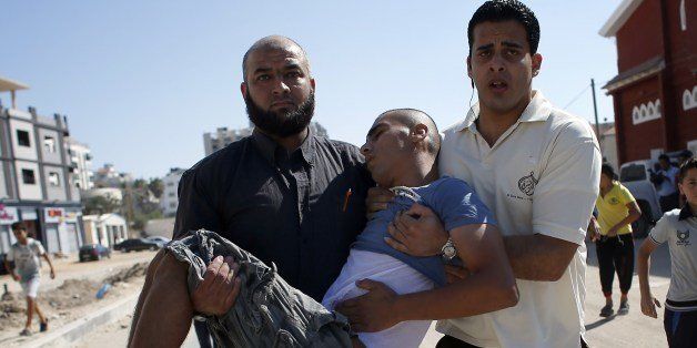 Palestinian employees of Gaza City's al-Deira hotel carry a wounded boy following an Israeli military strike nearby on the beach, on July 16, 2014. Four children were killed in Gaza City during the attack, medics said, in Israeli shelling witnessed by AFP journalists. All four were on the beach when the attack took place, emergency services spokesman Ashraf al-Qudra said, with several injured children taking refuge at a nearby hotel where journalists were staying. AFP PHOTO / THOMAS COEX (Photo credit should read THOMAS COEX/AFP/Getty Images)