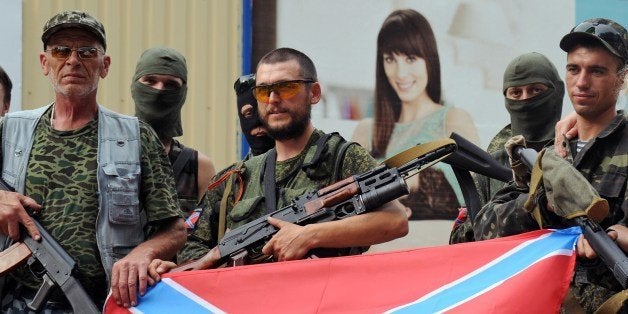 Pro-Russian militants pose on July 13, 2014 with the new Russia (novorossiya) flag in Donetsk, eastern Ukraine. Escalating clashes between pro-Kremlin separatists and Ukrainian forces today killed 12 civilians and forced the new Western-backed leader to cancel a pivotal meeting with Russian President Vladimir Putin at the World Cup in Brazil. An AFP correspondent at the morgue in Maryinka saw the corpses of eight people killed in clashes waged outside that village just west of Donetsk yesterday afternoon. AFP PHOTO / DOMINIQUE FAGET (Photo credit should read DOMINIQUE FAGET/AFP/Getty Images)