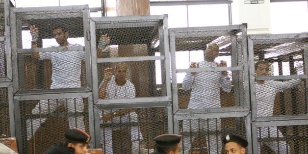 Defendants in the Marriott terror cell case in Cairo stand in cages in an Egyptian courtroom Monday, March 31, 2014, as they await their turn to speak about their request for bail. From left, Suhaib Saeed, a university student who donned a white t-shirt to cover one that compared his prison conditions to Guantanamo, Al Jazeera English correspondent Peter Greste, an Australian, Al Jazeera English bureau chief Mohamed Fahmy, who holds dural Canadian-Egyptian citizenship, and cameraman Baher Mohamed, an Egyptian. The three journalists are accused of falsifying news about Egypt and running a terror cell out of their temporary offices at the Marriott Hotel in Cairo. The judge again denied bail for the men, who've been held since Dec. 29. (Amina Ismail/MCT via Getty Images)