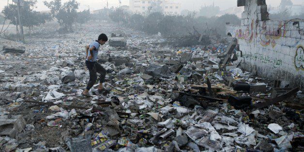 A Palestinian youth walks on debris as he inspects damages following an Israeli air strike in Gaza City, on July 24, 2014. Fifteen Palestinians were killed today when an Israeli shell slammed into a UN shelter where hundreds of civilians had taken refuge, sending the death toll in Gaza soaring to 788 despite world efforts to broker a ceasefire. AFP PHOTO / MOHAMMED ABED (Photo credit should read MOHAMMED ABED/AFP/Getty Images)