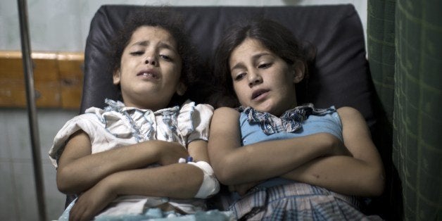 Palestinian girls who were wounded in an Israeli strike on a compound housing a UN school in Jabalia refugee camp in the northern Gaza Strip, wait for treatment at the Kamal Edwin hospital in Beit Lahia where victims from the attack were brought early on July 30, 2014. Israeli bombardments early on July 30 killed 'dozens' Palestinians in Gaza, including at least 16 at a UN school, medics said, on day 23 of the Israel-Hamas conflict. AFP PHOTO / MAHMUD HAMS (Photo credit should read MAHMUD HAMS/AFP/Getty Images)