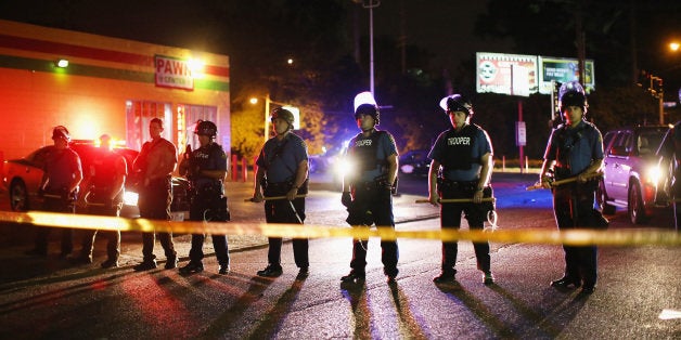 FERGUSON, MO - AUGUST 11: Police lock down a neighborhood on August 11, 2014 in Ferguson, Missouri. Police responded with tear gas as residents and their supporters protested the shooting by police of an unarmed black teenager named Michael Brown who was killed Saturday in this suburban St. Louis community. Yesterday 32 arrests were made after protests turned into rioting and looting in Ferguson. (Photo by Scott Olson/Getty Images)