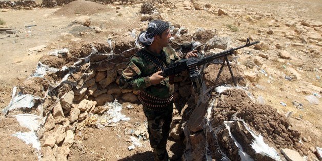 An Iraqi Kurdish Peshmerga fighter takes position on the front line in Bashiqa, a town 13 kilometres north-east of Mosul on A