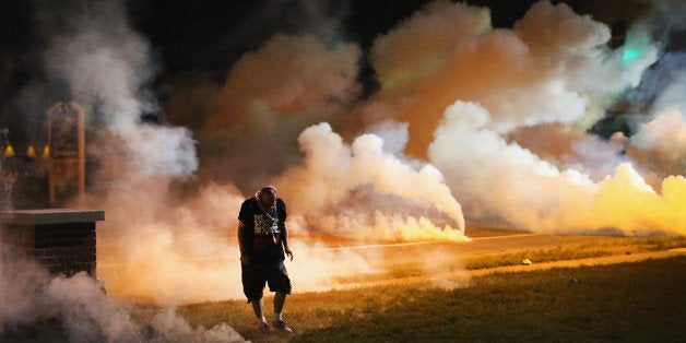 FERGUSON, MO - AUGUST 13: Demonstrators, protesting the shooting death of teenager Michael Brown, flee as police shoot tear gas into the crowd of several hundred after someone reportedly threw a bottle at the line of police on August 13, 2014 in Ferguson, Missouri. Brown was shot and killed by a Ferguson police officer on Saturday. Ferguson, a St. Louis suburb, is experiencing its fourth day of violent protests since the killing. (Photo by Scott Olson/Getty Images)