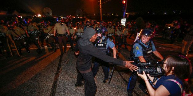 FERGUSON, UNITED STATES - AUGUST 18: A journalist reacts during a protest on August 18, 2014 for Michael Brown, who was killed by a police officer on August 9 in Ferguson, United States. Captain Ronald Johnson of the Missouri State Highway Patrol, makes statements to reporters as the protests continue in Ferguson. Some of the protesters were detained by the police during the clashes on Monday. The 18 year-old Brown was killed in a confrontation with a police officer in the St. Louis suburb of Ferguson, Missouri on August 09, 2014. Details of the fatal encounter continue to be disputed but racial tensions flared between the majority black community and predominantly white police force following his death. (Photo by Bilgin Sasmaz/Anadolu Agency/Getty Images)