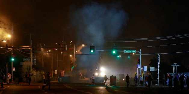FERGUSON, UNITED STATES - AUGUST 18: Protesters move away from tear gas fired by police officers during a demonstration on August 18, 2014 for Michael Brown, who was killed by a police officer on August 9 in Ferguson, United States. Captain Ronald Johnson of the Missouri State Highway Patrol, makes statements to reporters as the protests continue in Ferguson. Some of the protesters were detained by the police during the clashes on Monday. The 18 year-old Brown was killed in a confrontation with a police officer in the St. Louis suburb of Ferguson, Missouri on August 09, 2014. Details of the fatal encounter continue to be disputed but racial tensions flared between the majority black community and predominantly white police force following his death. (Photo by Bilgin Sasmaz/Anadolu Agency/Getty Images)