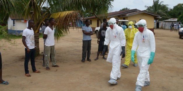 Inhabitants of the small city of Banjol, where three people inficted by Ebola virus died today, look at look at medical worke