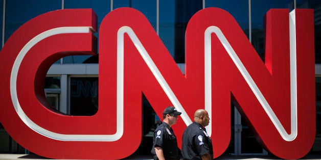 Security guards walk past the entrance to CNN headquarters, Tuesday, Aug. 26, 2014, in Atlanta. The corporate parent of CNN,