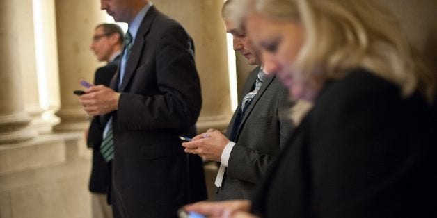 Reporters check their smartphones while waiting outside US House Speaker John Boehner's office at the US Capitol in Washington on September 30, 2013 as a possible government shutdown looms. The United States stumbled to within hours of a government shutdown, as a budget duel between President Barack Obama and Republicans threatened America with a self-inflicted economic wound. AFP PHOTO/Nicholas KAMM (Photo credit should read NICHOLAS KAMM/AFP/Getty Images)