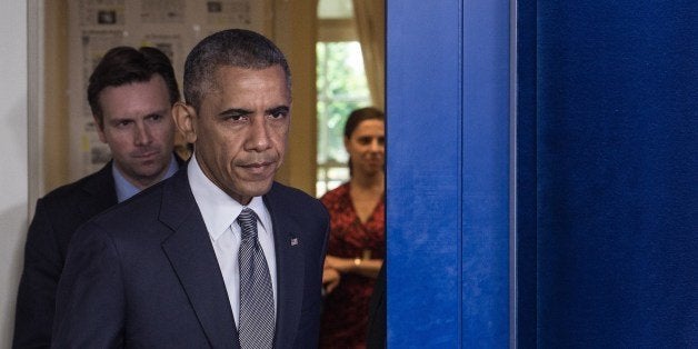 US President Barack Obama, followed by Press Secretary Josh Earnest, arrives to make a statement on the situation in Ukraine in the White House briefing room in Washington,DC on July 18, 2014. President Obama said Friday that a missile fired from rebel-held territory in Ukraine downed the Malaysian plane and that one American was among the dead. 'Their deaths are a outrage of unspeakable proportions,' Obama told reporters as he pressed for an international investigation. AFP PHOTO/Nicholas KAMM (Photo credit should read NICHOLAS KAMM/AFP/Getty Images)