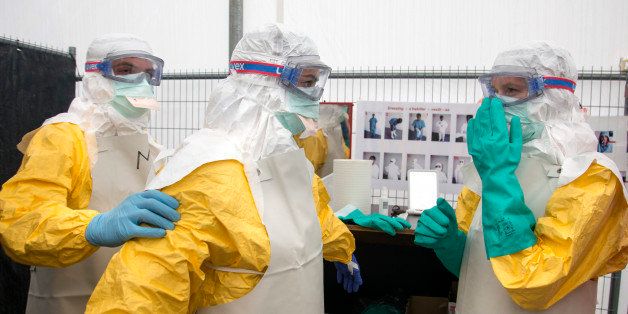 Participants help each other with their suits during a training course to instruct non-governmental organisation (NGO) workers and doctors on how to deal with the Ebola virus in Brussels on Tuesday, Aug. 26, 2014. The course, provided by Doctors Without Borders, trains volunteer and medical personnel on precautions to take when entering a zone that contains the Ebola virus.(AP Photo/Olivier Matthys)